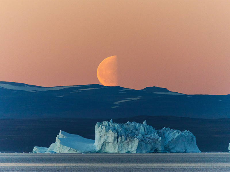 The moon hanging low in the sky over Greenland